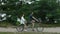 A young couple rides a tandem two-seater bike along the riverbank