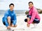 Young couple of runners tying shoelace at the seaside