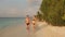 Young couple running on beach in surf holding hands. Newlyweds on honeymoon enjoying vacation. Lovers splashing blue