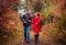 Young couple runs in autumn forest among colorful trees