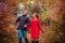 Young couple runs in autumn forest among colorful trees