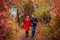 Young couple runs in autumn forest among colorful trees