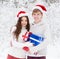 Young couple in santa claus hats hugging and holding gifts