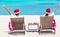Young couple in Santa hats relaxing on beach