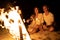 Young couple on the sea beach sitting bonfire and toasting marshmallows on a stick. A romantic date by the fire. Tourism
