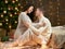 Young couple sit on floor in dark wooden interior with lights. Romantic evening and love concept. New year holiday. Christmas ligh