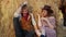 A young couple sits on hay in the farm. Happy smiling cowboy and woman spend time together