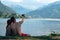 A young couple sits on the lake take pictures, take selfies, enjoy the views, vacation, relax. couple in love Zell am see in