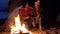 Young couple sitting by the fire. camping with tents by the sea. spring evening