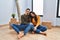 Young couple sitting on the floor at new home looking sleepy and tired, exhausted for fatigue and hangover, lazy eyes in the