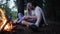Young couple sitting in a forest fire. The guy kisses the girl