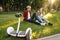 Young couple sitting on the grass near gyro board