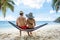 Young Couple Sitting On Hammock At Beach