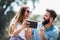 Young couple sitting on a park bench and uses a digital tablet for online shopping