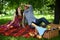 Young couple sitting on picnic blanket while boyfriend feeding