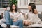 Young couple sitting on a sofa in their home relaxed talking and having a drink