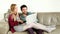 Young couple sitting and talking on couch looking at laptop at home