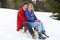 Young Couple On A Sled In Alpine Snow Scene