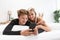 Young couple with smartphone relaxing while reclining on boyfriend sitting on the bed