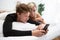 Young couple with smartphone relaxing while reclining on boyfriend sitting on the bed i