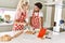 Young couple smiling happy mixing ingredients to make dough for homemade bread