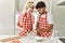 Young couple smiling happy mixing ingredients to make dough for homemade bread at kitchen