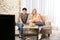 Young couple with snacks watching TV on sofa