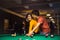 Young couple spending time in billiard room. Boyfriend teaching his girlfriend to playing billiard