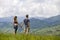 Young couple, sportive man and slim woman holding hands outdoors on background of beautiful mountain landscape on sunny summer day