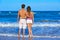 Young couple standing looking at the beach rear