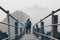 Young couple standing on mountain peak with stairs going down during sunrise foggy morning in Hpa-An, Myanmar