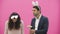 Young couple standing on a pink background. During this man holds Easter eggs in his hands, his wife lowered his head