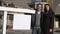A young couple stands in front of Real Estate Sign