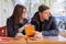 Young couple of students study in outdoor cafe, drink coffee tea, eat croissants, background is spring city street