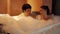 Young couple taking a bubble bath in the bathtub at night