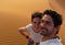 A young couple taking a self picture while climbing to the top of the Great Sand Dune in the red dune sea of Erg Chebbi, Morocco