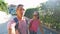 Young couple taking selfie portrait during walking sunny empty road with green fence