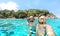 Young couple taking selfie in tropical scenario with waterproof camera - Boat trip snorkeling excursion at Similan islands