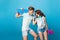 Young couple of teenagers having fun on blue background in studio. They wear T-shirts, jeans shorts, hold skateboards
