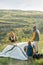 Young couple and their little son standing on top of mountain while putting tent