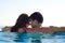 Young Couple Together in an Infinity Swimming Pool. Rear View of Honeymoon Couple at Luxury Resort. Travel and Summer Vacation.