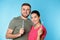 Young couple with toothbrushes on color background