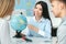 Young couple in a tour agency communication with a travel agent travelling concept globe showing destination