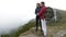 Young couple of tourists kissing on the edge of mountain enjoying the amazing valley panorama with forest shrouded in thick fog -