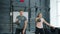 Young couple training in gym weightlifting squatting with kettlebells together