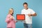 Young couple two friends guy girl in white pink t-shirts posing isolated on blue background. People lifestyle concept