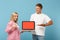 Young couple two friends guy girl in white pink t-shirts posing isolated on blue background. People lifestyle concept