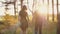 Young couple walk in forest at beautiful sunset. Sun rays shine. Lovers in nature. Slow mo, steadicam shot, backview