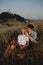 Young couple on a walk in nature at dusk in countryside, sitting and resting in long grass.