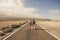 Young couple walk together on a long straight road in the middle of a desert nowhere place - life and love and relationship